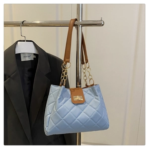 Detalle del bolso tote acolchado azul claro con ribete de cuero marrón y cierre dorado