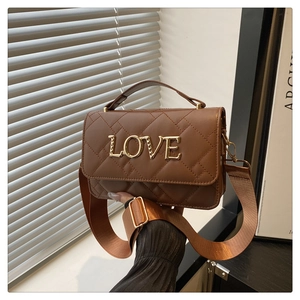 Detailed close-up of brown quilted shoulder bag with gold LOVE lettering and wide strap