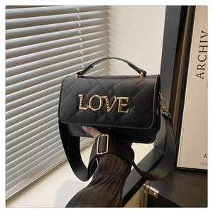 Close-up of black quilted bucket bag featuring gold LOVE lettering and chain strap
