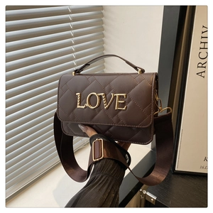 Close-up of quilted leather handbag with gold metal LOVE lettering and top handle