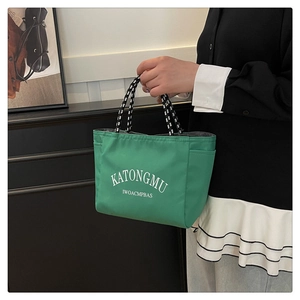 Detail view of bright green nylon tote bag with polka dot handles and white lettering