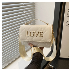 Macro detail of beige quilted barrel bag featuring gold LOVE lettering and wide strap