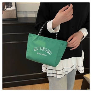 Close-up of green nylon tote bag with white lettering and bicolor rope handles