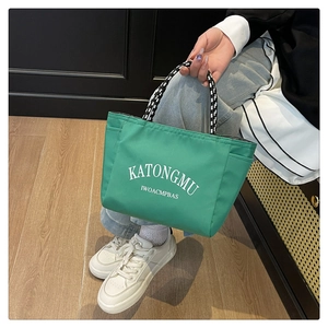 Detail of green tote bag featuring woven handles and KATONGMU letter print design