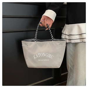Close-up of gray nylon tote bag with white lettering and woven rope handles
