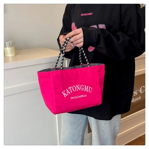 Detailed view of pink tote bag with white lettering and woven rope handles for women