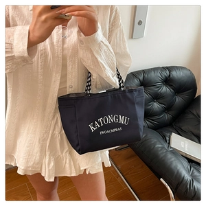 Detail of navy tote bag with woven handles and side pocket shown in lifestyle setting