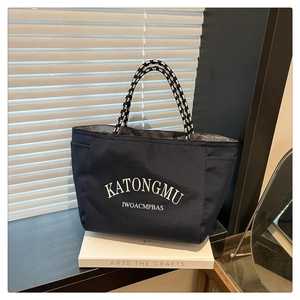 Detail of dark blue tote bag featuring white lettering and woven rope handles