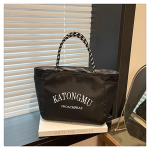 Detail of black tote bag with white KATONGMU letter print and woven rope handles