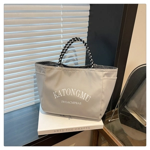 Close-up of minimalist gray canvas tote bag featuring rope handles and letter printing