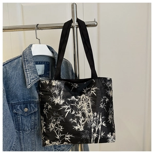 Détail d'un grand sac cabas avec imprimé bambou blanc sur tissu noir suspendu