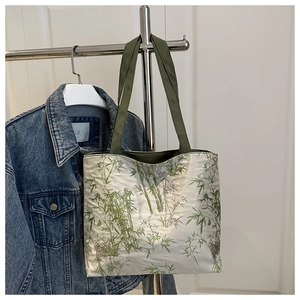 Détail du motif en bambou à l'encre et des poignées vertes sur le sac cabas
