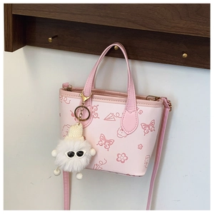 Detail view of pink leather bucket bag with cartoon patterns and plush charm accessory