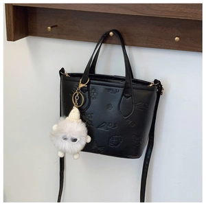 Detail of black leather bucket bag with butterfly embossing and plush ball charm