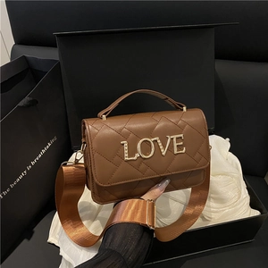 Brown quilted cylinder bag with LOVE lettering and chain strap in a gift box