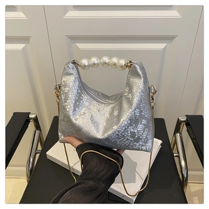 Detail of silver snake pattern handbag featuring pearl handle and gold chain strap