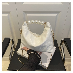 Detail of white snakeskin texture bag with large pearl handle and gold chain strap