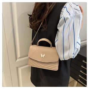 Gros plan du sac bandoulière beige matelassé avec une boucle papillon en métal chic