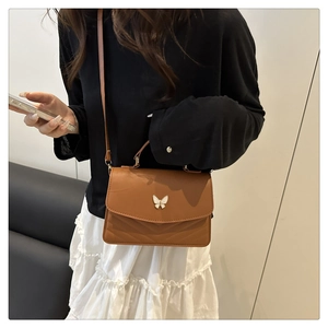 Sac bandoulière en cuir caramel avec fermoir papillon et surpiqûres en V