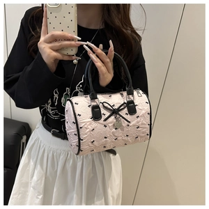 Close-up of pink seersucker Boston bag featuring black bow prints and heart charm