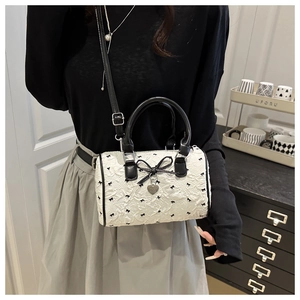 Détail du sac Boston en seersucker blanc avec broderie nœud et pendentif cœur