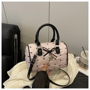 Detail of pink seersucker Boston bag featuring black bows and heart-shaped metal pendant