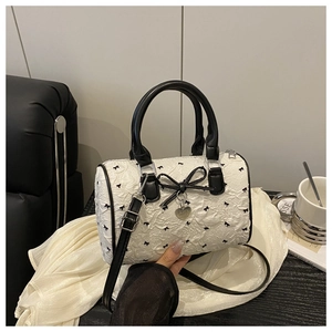 Detail of white seersucker Boston bag with black floral bows and heart pendant