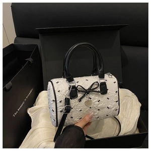 Close-up of white seersucker Boston bag with black bows in an elegant gift box