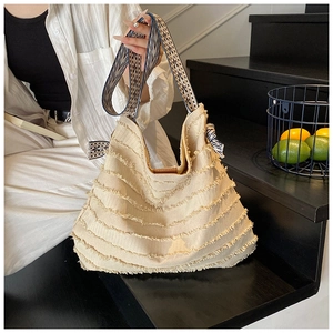 Détail du sac cabas en toile beige avec franges bohèmes et bandoulière tissée à rayures