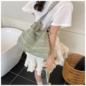Détail du sac cabas vert clair à bords effilochés avec bandoulière géométrique