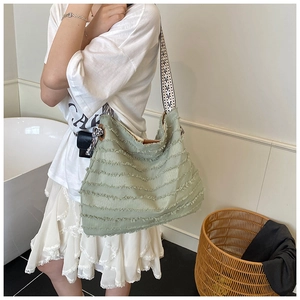 Détail d'un sac cabas vert avec texture à franges et bandoulière géométrique tissée