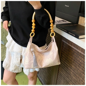 Detail of pink floral tote bag with wooden bead handle and stylish grey tassel accent