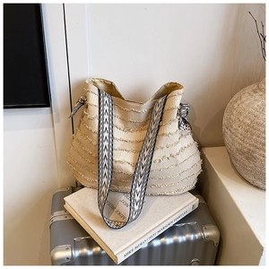 Détail d'un cabas en toile beige avec franges et bandoulière à motifs géométriques