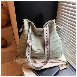Détail du sac hobo en toile vert clair avec coutures effilochées et sangle géométrique