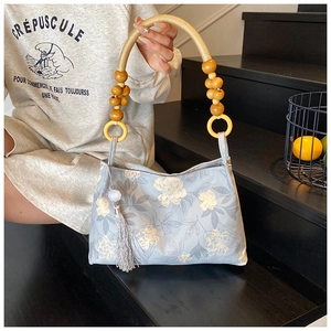 Detail of light blue floral tote bag with wooden bead handle and silk tassel on stairs