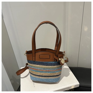 Détail du sac seau tressé multicolore avec anses en cuir marron et pendentif doré
