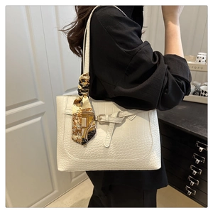 Close-up of white crocodile pattern tote bag with decorative yellow printed silk scarf