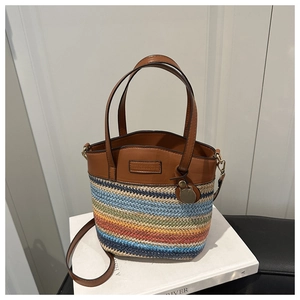 Détail du sac seau tissé contrasté avec poignées en cuir marron et breloque chat