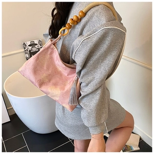Pink floral tote with wooden bead handle and long grey tassel worn by a model