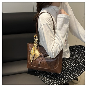 Detailed view of brown crocodile texture tote bag with elegant silk scarf and buckle