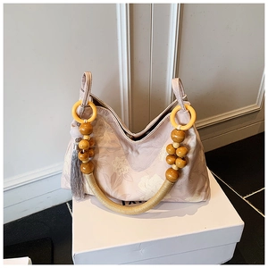 Detail of floral tote bag with wooden bead handle and decorative grey tassel charm