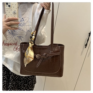 Detail of dark brown faux crocodile tote bag with decorative scarf on shoulder strap