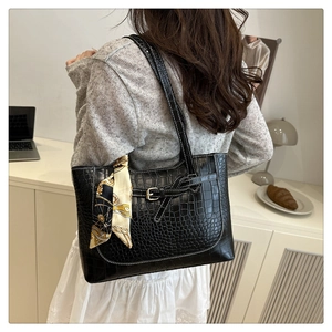 Detail of black crocodile texture tote bag with elegant silk scarf and buckle accent