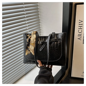 Detail of black crocodile texture tote bag with silk scarf and decorative belt strap