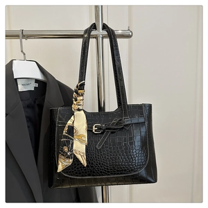 Detail of black crocodile texture tote bag with elegant silk scarf and metal buckle