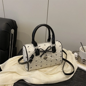 White seersucker Boston bag with black floral bows and silver heart pendant detail