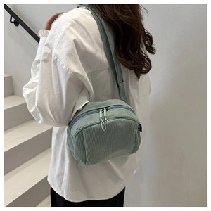 Detail view of mint green corduroy crossbody bag with double zippers and wide strap