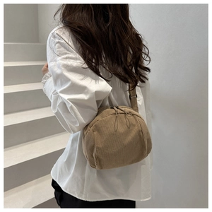 Detail view of vintage corduroy texture and dual zippers on a crescent crossbody bag