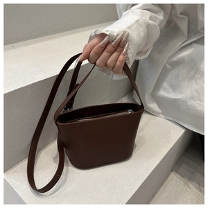 Detail of dark brown leather bucket bag with embossed logo and metal zipper closure