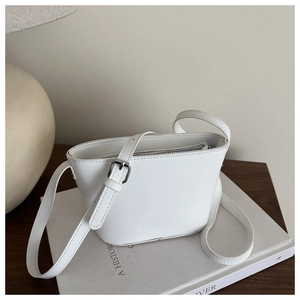 Detail der weißen Beuteltasche mit FANYISSA Logo und verstellbarem Gurt auf Büchern
